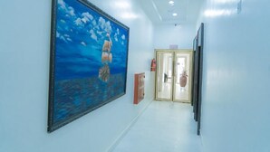 A hallway with a large painting of a seascape, a door, and a fire extinguisher. - Muna Suites Owerri (Owerri)