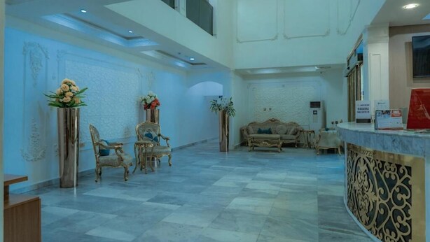 A spacious lobby with a high ceiling, a reception desk, and ornate wall decorations. - Muna Suites Owerri (Owerri)