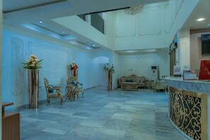 Un hall d’entrée spacieux avec un plafond haut, un comptoir d’accueil et des décorations murales élaborées.
