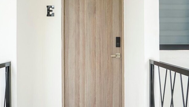 A hallway with a wooden door, a small step leading to the entrance, and a black metal railing on the right. - Private Loft Cozy & Modern (San Luis Potosi)