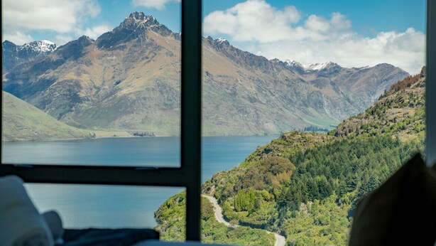 A mountain landscape with a lake and a road winding through a forested area. - Sam`s Sanctuary | Stunning Views & Spacious Home (Queenstown)