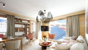 Una sala de estar moderna con comedor, ventanas amplias con vista a un paisaje nevado y un techo con una lámpara de techo original.