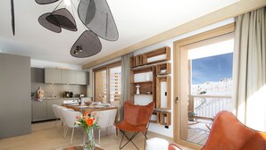 Una sala de estar moderna con comedor, cocina y balcón con vista a la montaña.