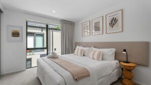 A modern bedroom with a large bed, a view to the outside, and artwork on the wall. - Skippers Rest | Close to ski fields & parking (Queenstown)