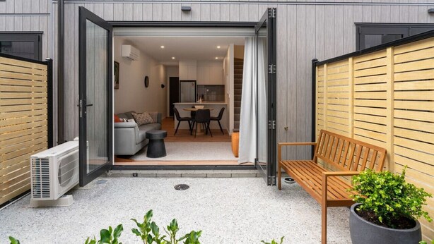 A modern apartment with an open-plan living area, a kitchen, and a small balcony with a bench and potted plant. - Skippers Rest | Close to ski fields & parking (Queenstown)