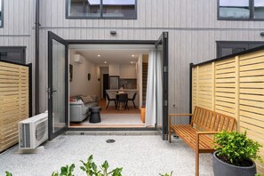 A modern apartment with an open-plan living area, a kitchen, and a small balcony with a bench and potted plant. - Skippers Rest | Close to ski fields & parking (Queenstown)