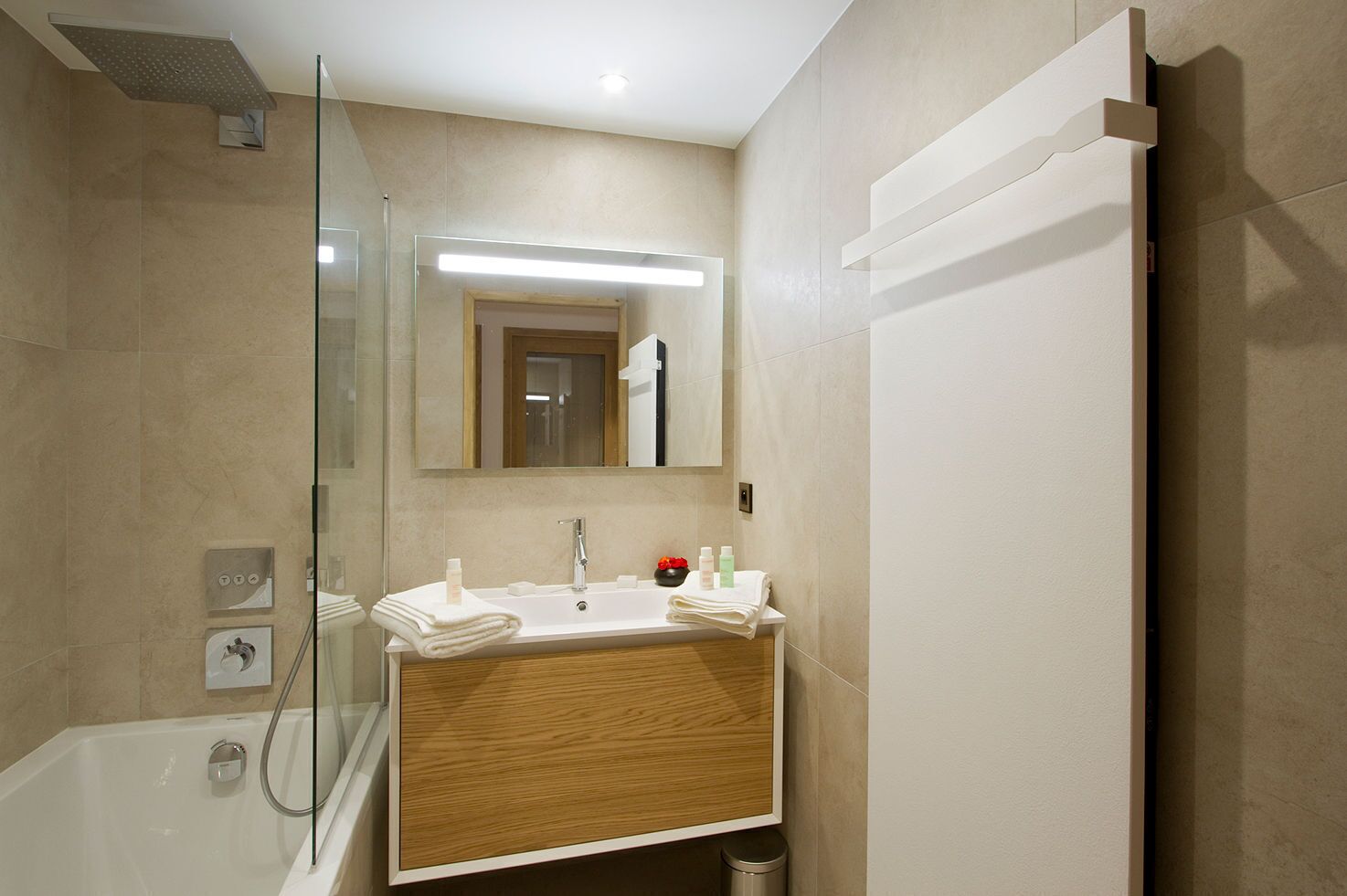 Une salle de bain moderne avec une douche à parois de verre, un meuble-lavabo en bois et un grand miroir.
