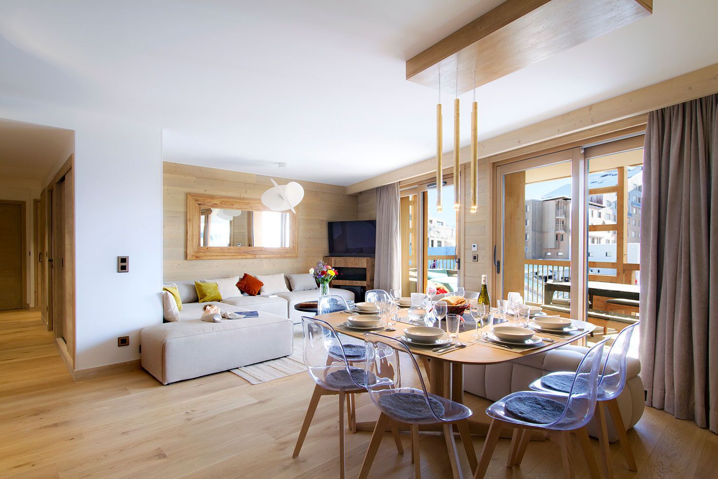 Een moderne woonkamer met een eetgedeelte, houten vloeren en grote ramen met uitzicht op de stad.