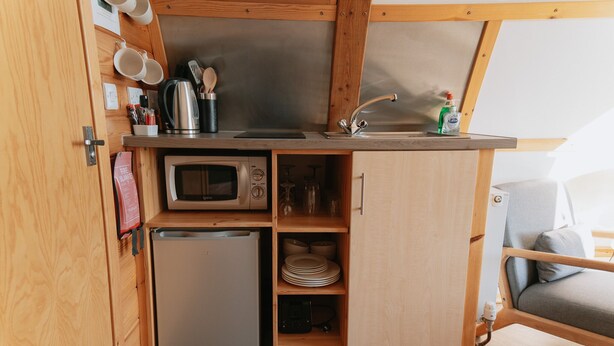 Una cucina compatta con un forno a microonde, un piccolo frigorifero e un lavandino.