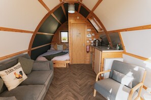Acogedor dormitorio tipo loft con cama, sofá, sillón, kitchenette y vistas al exterior.