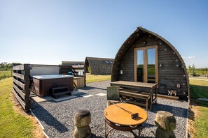 Eine rustikale Holzhütte mit Whirlpool, einer Holzterrasse und einem runden Tisch.