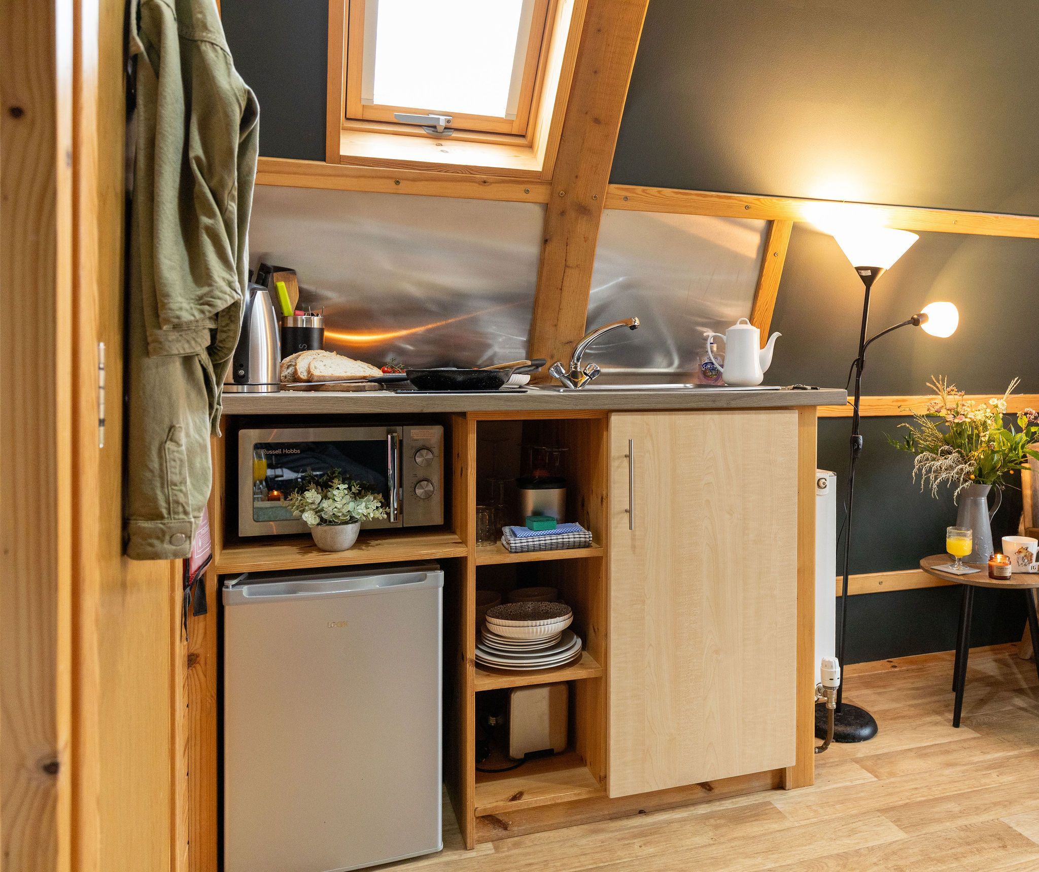 A compact kitchen with a built-in microwave, a small refrigerator, and wooden cabinets.