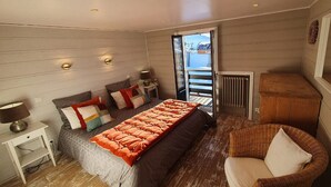 Une chambre à coucher avec un lit, une chaise, une table de chevet et une fenêtre donnant sur la mer.