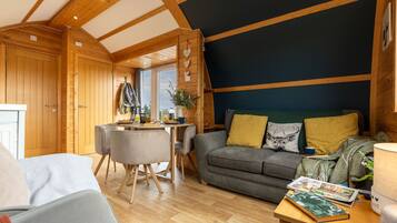 A cozy cabin interior with a dining area, a sofa with cushions, and a table with a magazine.