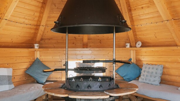 A cozy attic room with a wood stove, wooden walls, and a sloped ceiling.