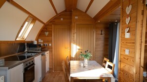 A cozy kitchen with wooden walls, a dining table with chairs, and a built-in oven.