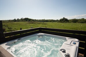 A hot tub with a view of a grassy field and trees. - Luxury Rural Pod With Ensuite & Hot Tub (Newton Stewart)
