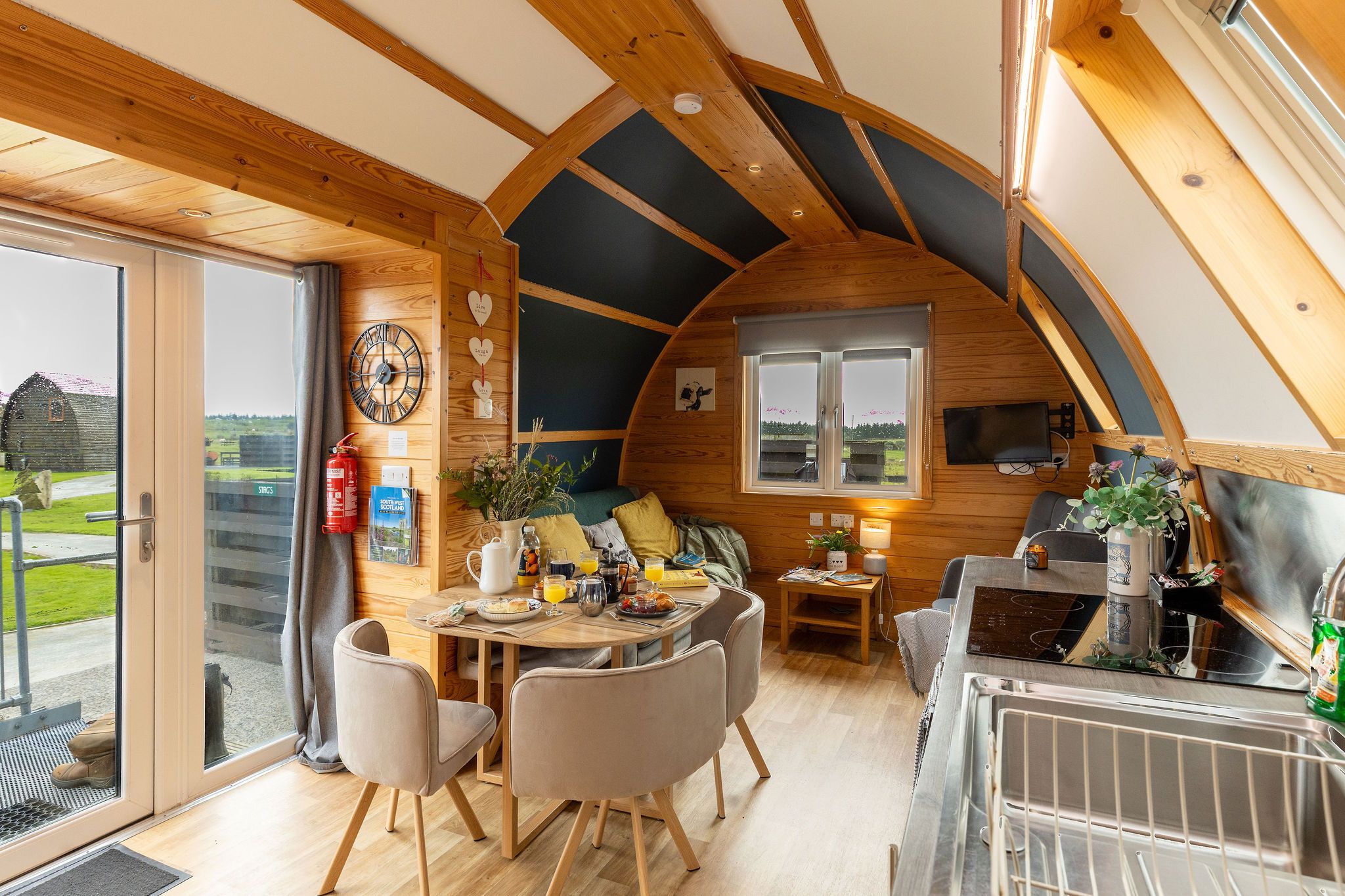 A cozy, well-lit interior with a dining area, seating, and a kitchen.
