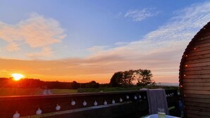 A hot tub on a deck with a sunset view.