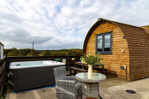 A cozy outdoor area with a hot tub, wicker furniture, and a wooden cabin structure.
