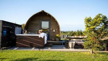 Een houten chalet met een veranda, een eettafel gedekt voor twee personen en een kleine tuin.