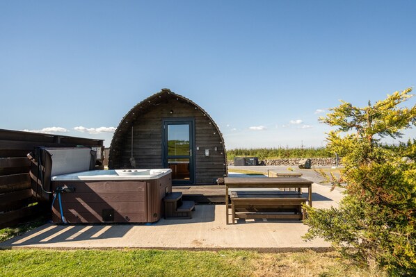 Eine Holzhütte mit Whirlpool, einer Holzbank und einem kleinen Tisch.