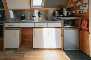 Eine kleine Küche mit Spüle, Herd, Mikrowelle und Kühlschrank.