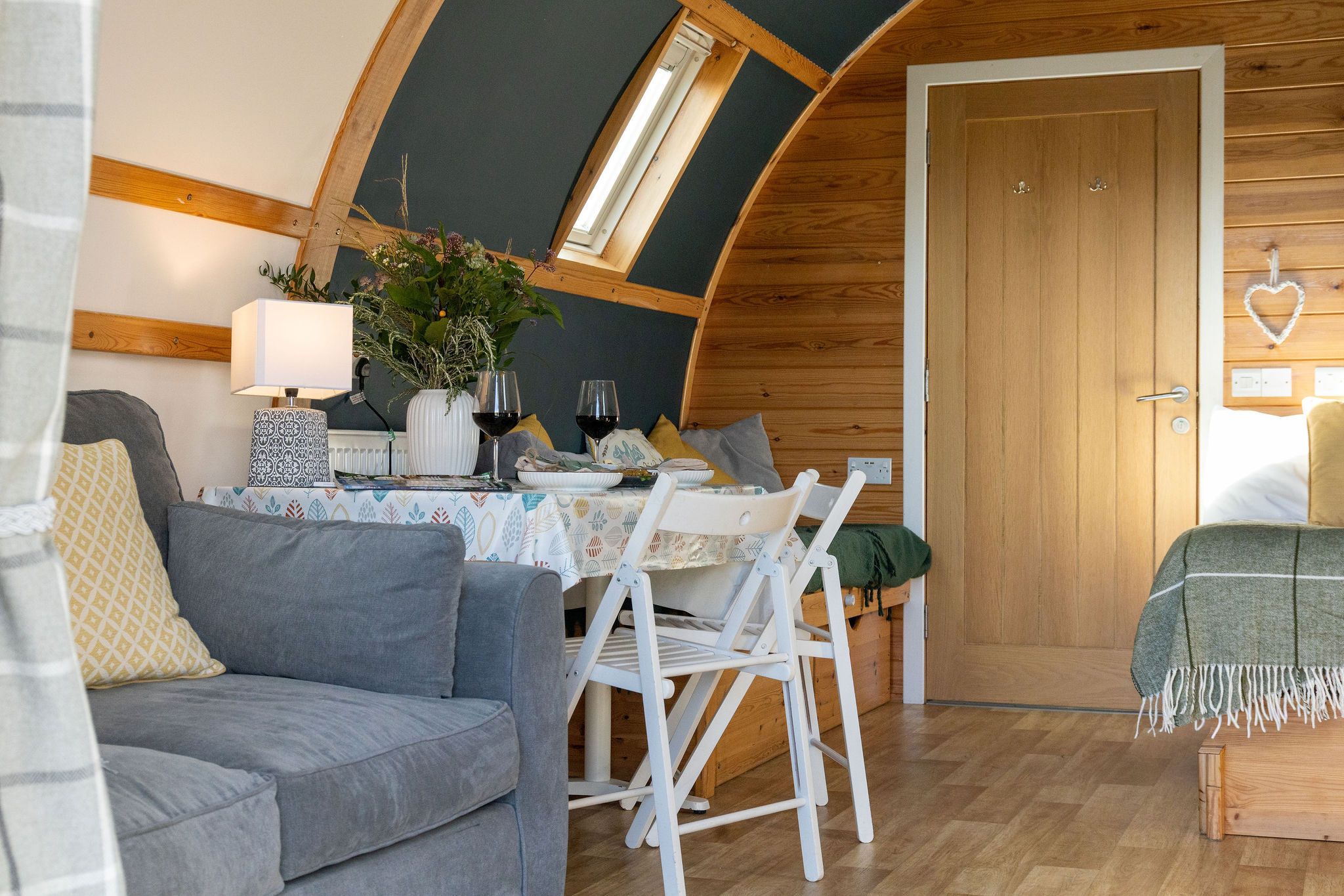 Ein gemütliches Zimmer mit Esstisch, Stühlen, einer Couch, einer Lampe und einer Pflanze.