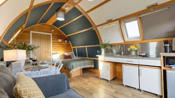 Een knus interieur met een gebogen plafond, een eethoek, een kitchenette en een bed met uitzicht.