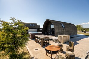 Un bâtiment moderne à toit incurvé, doté d’un jacuzzi, de meubles en bois et d’un espace barbecue.