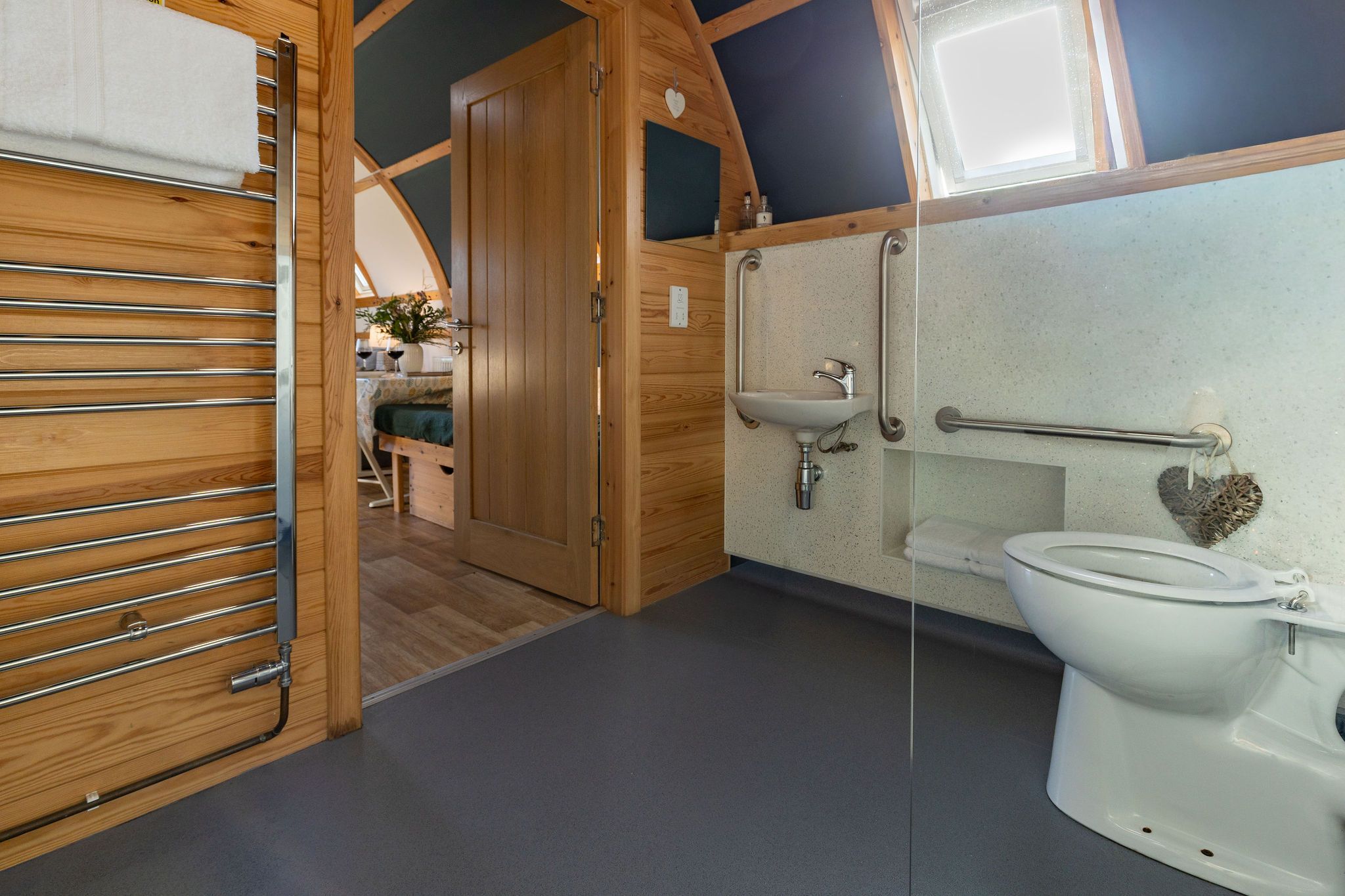 Een kleine, goed verlichte badkamer met toilet, wastafel en handdoekhouder.
