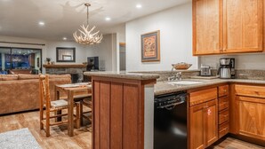 A modern kitchen with wooden cabinets, a dining area with a table and chairs, and a view of the living room.