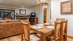 A dining area with a wooden table, woven chairs, and a chandelier.