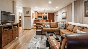 A modern living room with a large leather sofa, a flat-screen TV, and a wooden cabinet.