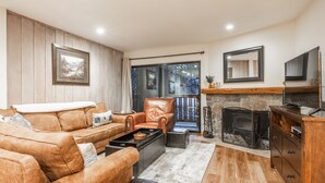 A living room with a fireplace, leather sofas, a coffee table, and a stone fireplace surround.