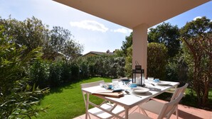 An outdoor patio with a white table and chairs, surrounded by greenery and a clear sky. - Mirto Marino by Interhome (Costa Rei)