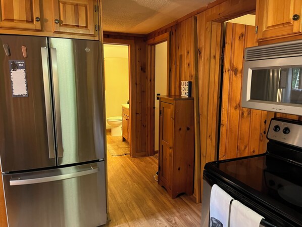A kitchen with wooden cabinets, a stainless steel refrigerator, a microwave, and a stove.
