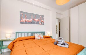 A bedroom with a large orange bed, a teal headboard, a painting of flamingos, and a towel rack with towels. - 5 bedroom cozy home in Lavagna (Lavagna)