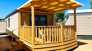 A wooden decked structure with a covered porch, a staircase, and a window. - Camping Village Capo d'Orso by Interhome (Palau)