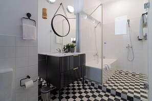 A modern bathroom with a black and white checkered floor, a glass shower enclosure, a black vanity with a mirror, and a white sink. - 3BR Atrium Penthouse by Cismigiu - Bright & Spacious with Balcony (Bucharest)