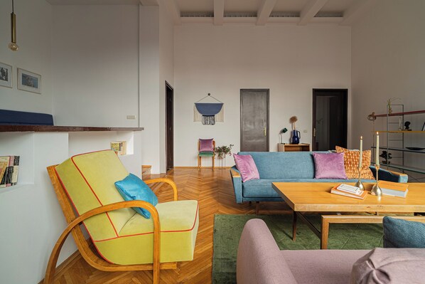 A modern living room with a wooden floor, a blue sofa, a yellow armchair, and a wooden coffee table.