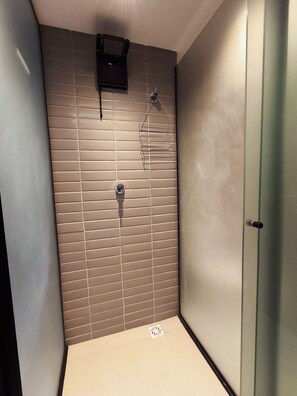 A bathroom with a shower, tiled walls, and a door. - Alta Garden (João Pessoa)