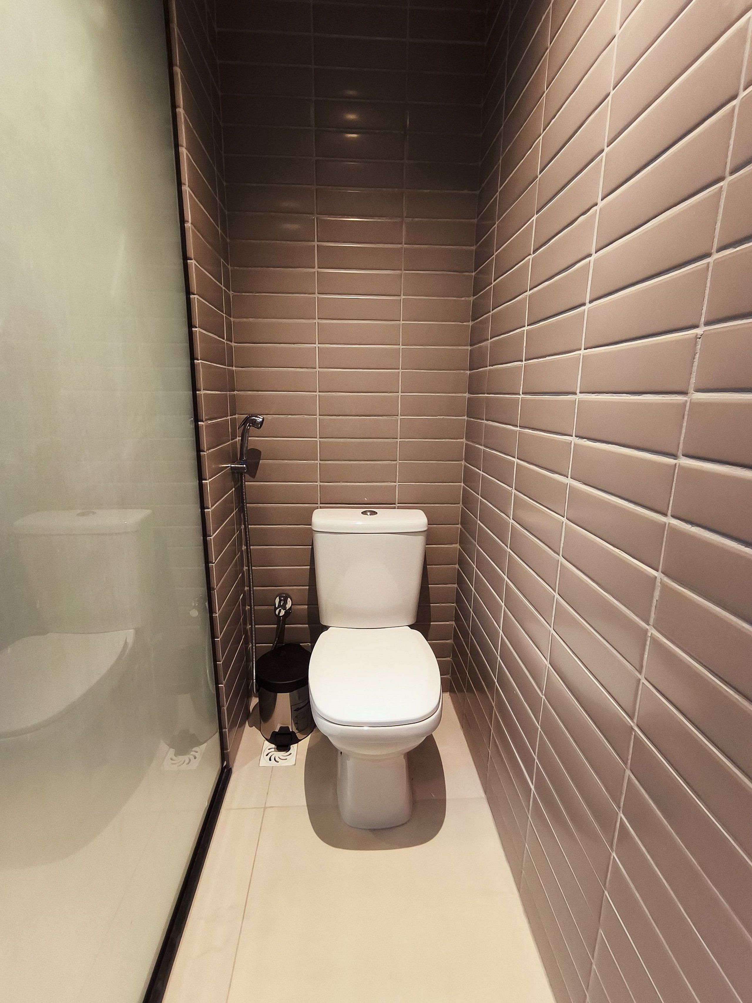 A compact bathroom with a toilet, a small sink, and a shower.