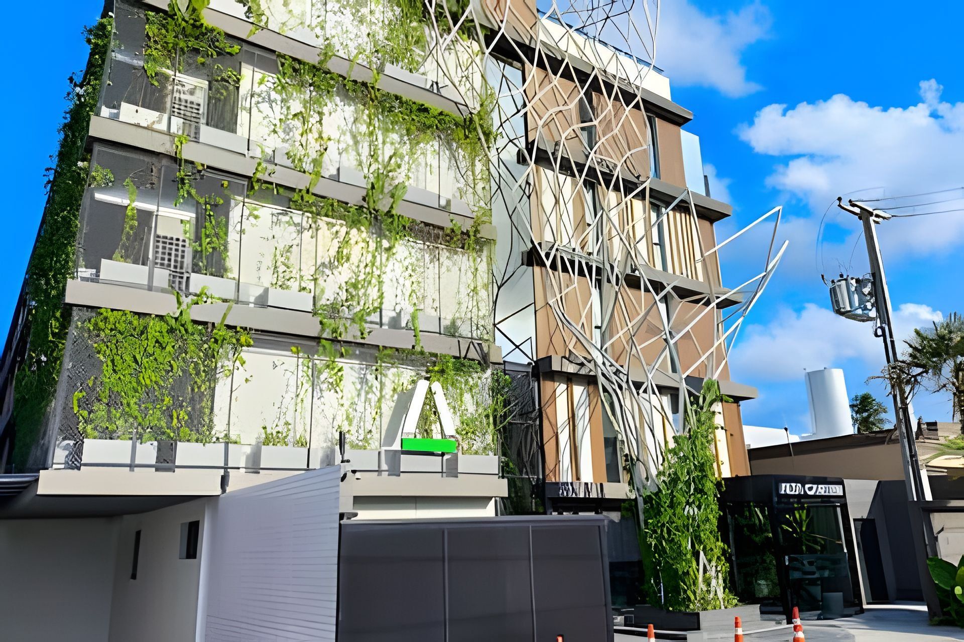 Un edificio moderno con una fachada cubierta de vegetación, una entrada visible y un cielo despejado.