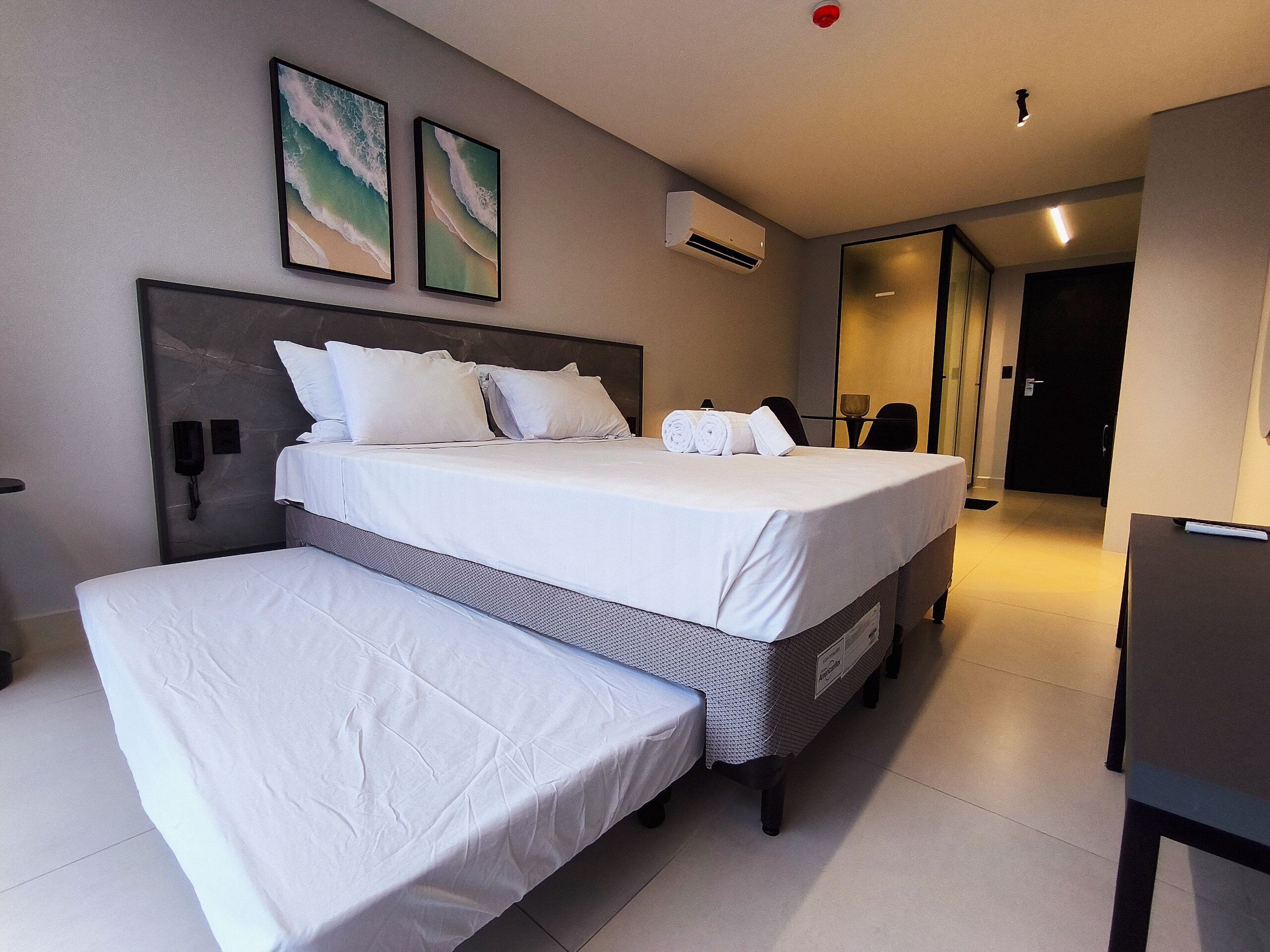 Een hotelkamer met twee bedden, een bureau en een badkamer zichtbaar door een open deur.