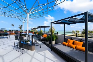 Terraço no telhado com área de estar ao ar livre, mesa de bilhar e vista para o oceano.