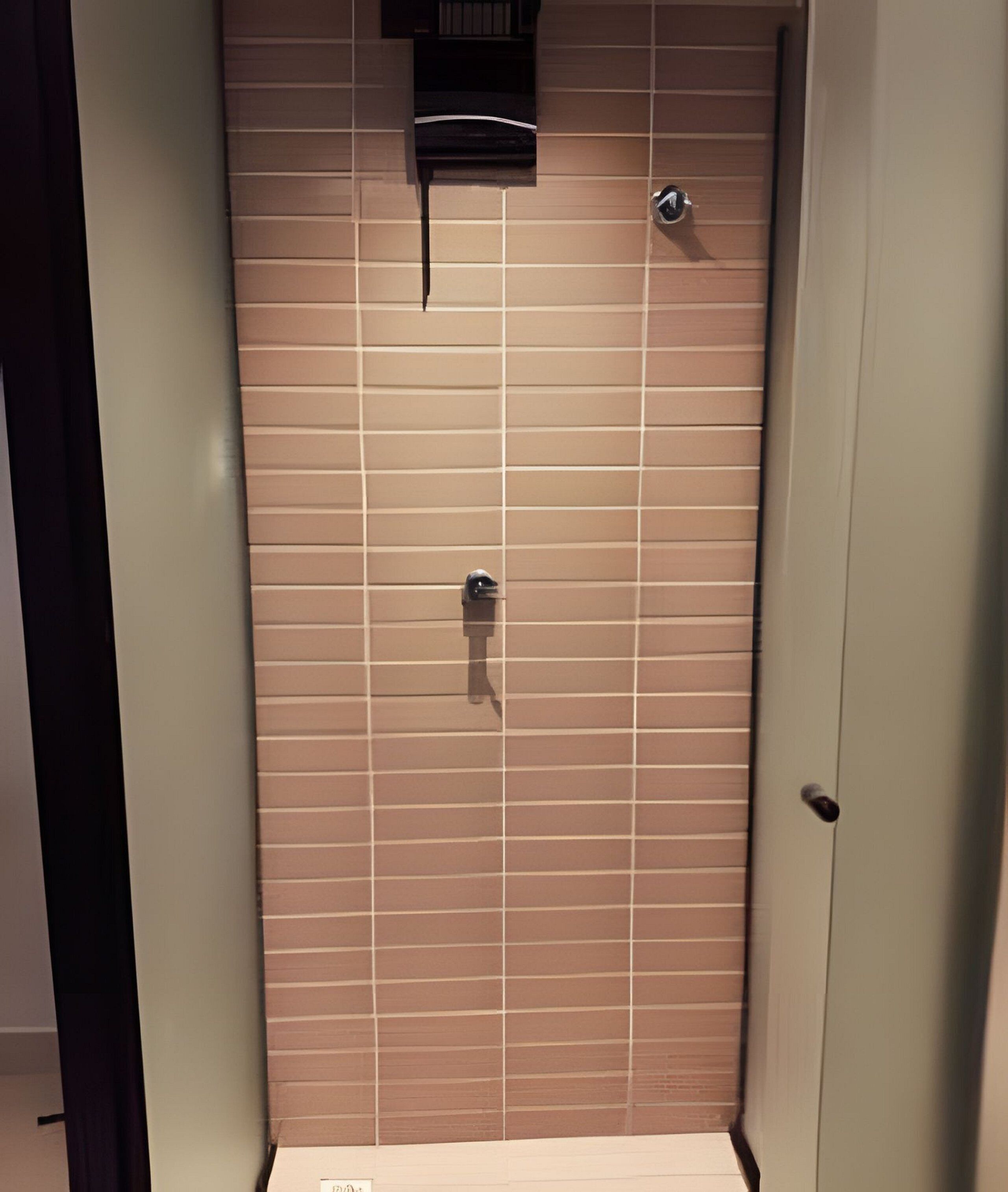 A bathroom with a tiled wall, a shower, and a toilet.