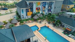 A hotel with a swimming pool, outdoor seating, and a mural on the building. - Westbrook Hotel & Offices (Owerri)