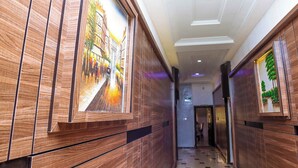 A hallway with wooden paneling and framed artwork depicting a street scene. - Westbrook Hotel & Offices (Owerri)