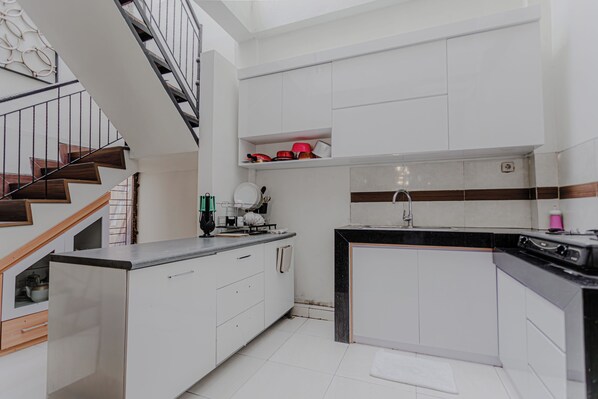 A modern kitchen with white cabinetry, a black countertop, and a stainless steel stove.